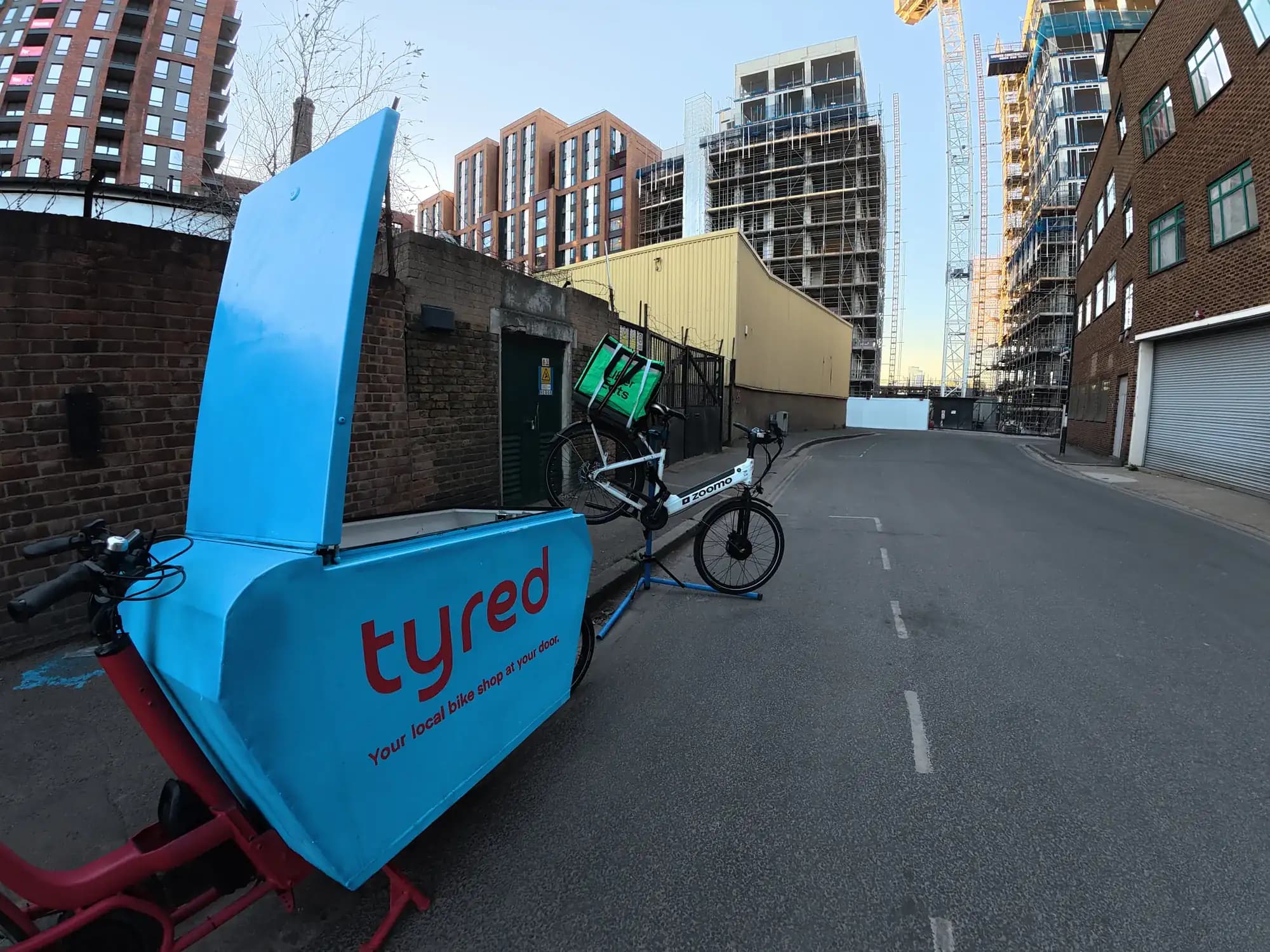 A Tyred cargo bike parked beside a delivery e-bike on a London street.