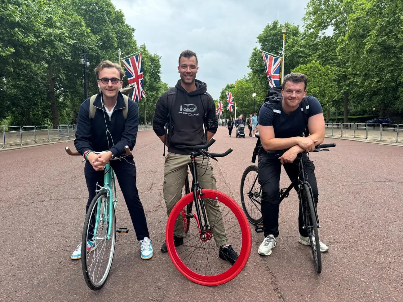 The Tyred founding team with their bikes on The Mall in London, Union Jack flags lining the avenue.