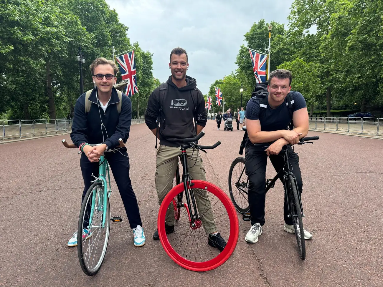 The Tyred founding team with their bikes on The Mall in London, Union Jack flags lining the avenue.