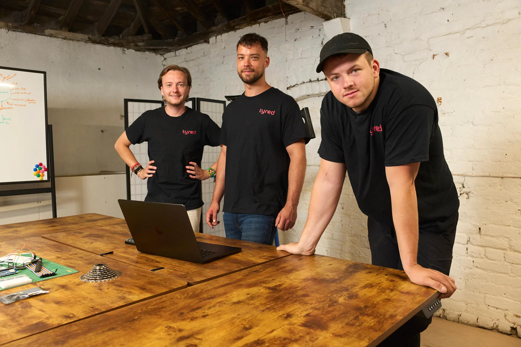 The Tyred founding team in their London workshop, with bike parts and prototyping kit on the desk.